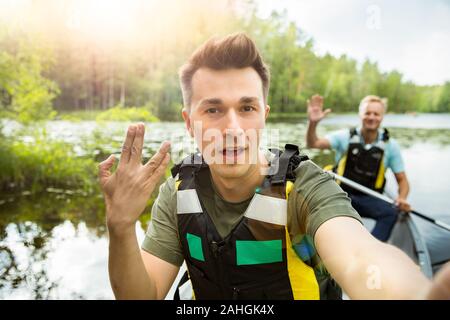 Zwei Männer im Leben haben Kanufahren im Waldsee. Wasseroberfläche mit Seerosen bedeckt. Touristen, die in Finnland reisen und Abenteuer erleben. Freunde Takin Stockfoto