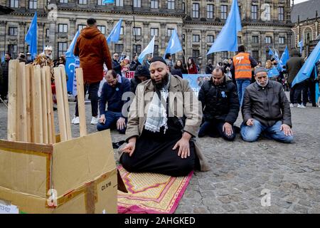 Amsterdam, Niederlande. 18 Mai, 2019. Muslimische Demonstranten führen Ihre 12.00 Uhr Gebet während einer Kundgebung. Uiguren und Sympathisanten sammeln am Dam Square in Amsterdam ihre Unterstützung mit ethnischen Chinas Uiguren und Protest gegen das, was sie als die Unterdrückung der Uiguren in China von der Regierung dieses Landes zu zeigen. Credit: Niels Wenstedt/SOPA Images/ZUMA Draht/Alamy leben Nachrichten Stockfoto