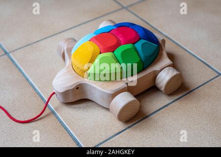 Schöne Ziehen entlang Holz Spielzeug in der Form einer Schildkröte mit zehn rainbow Blöcke, die shell der Schildkröte. Stockfoto