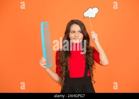 Wachsendes Haar Empfehlung. Kind mit lockigem Haar. Friseur für Kid. Beauty und Mode. denken an neue Frisur. Schulmädchen halten großen Kammaufsatz. Pflege und bürsten Sie Ihr Haar. Kleines Mädchen lange Haare. Stockfoto