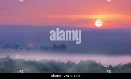 Eine afrikanische Sonnenaufgang über der Masai Mara in Kenia, mit einem weichen Fokus neblige Landschaft auf dem Boden, Schuß aus einem Heißluftballon. Stockfoto