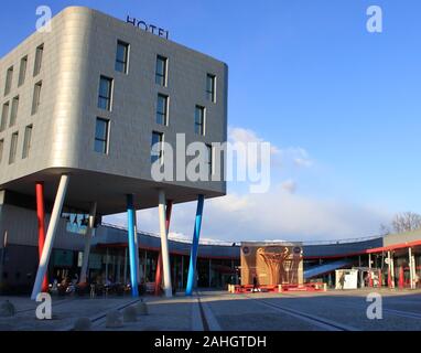 Modernes Hotel mit Stahl Fliesen, Italienische Alpen Landschaft, im Jahr 2006 die Winter Olympiade gebaut. Sie sehen eine Reproduktion der Olympischen Fackel aus Holz Stockfoto