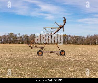 Rostige, alte Drehmittelpunkt Bewässerungssystem in abgeernteten Maisfeld mit Bäumen, blauer Himmel und weiße Wolken im Hintergrund Stockfoto