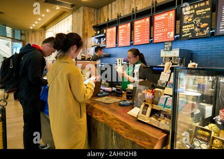 SHENZHEN, China - ca. Februar 2019: Frau kaufen Kaffee im Starbucks in Shenzhen. Stockfoto