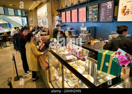 SHENZHEN, China - ca. Februar 2019: Frau kaufen Kaffee im Starbucks in Shenzhen. Stockfoto