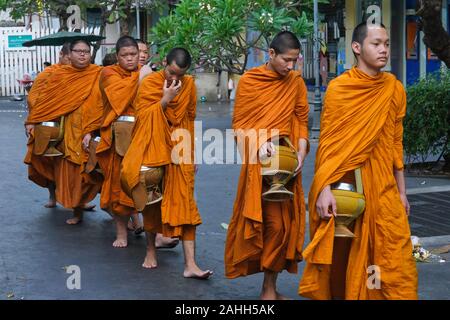 Junge Novizin buddhistische Mönche Resident in Wat Mahathat in Bangkok, Thailand, mit ihren Almosen klangschalen auf Ihren üblichen morgen Almosen zu Fuß Stockfoto