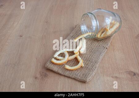 Hohe Betrachtungswinkel der kandierten Orangenschale in Glas Container auf Holz- Hintergrund Stockfoto