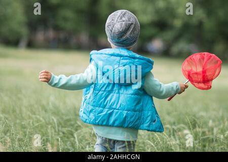 Fröhliches Kind spielen in einem Feld mit Insekt net im Sommer. schmetterlingsnetz fangen Schmetterlinge Stockfoto