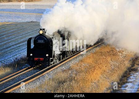 VR Hr1-Klasse Dampflok Ukko-Pekka 1009 ziehen Wagen an einem Wintermorgen durch ländliche Landschaft in Paimio, Finnland. Stockfoto