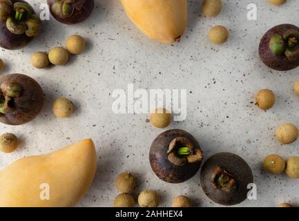 Flach Top view Komposition mit frischen Reifen mangosteen, longan und Mango Früchte auf dem Papier Hintergrund. Gesund essen mit Kopie Raum Stockfoto