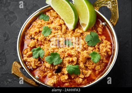 Huhn keema in der traditionellen indischen Kupfer kadai an dunklen Schiefer Hintergrund. Kheema ist die indische und pakistanische Küche Teller curry mit Hackfleisch und spic Stockfoto