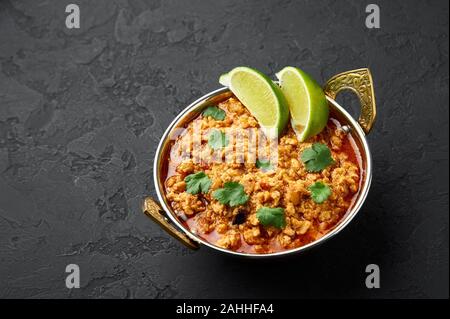 Huhn keema in der traditionellen indischen Kupfer kadai an dunklen Schiefer Hintergrund. Kheema ist die indische und pakistanische Küche Teller curry mit Hackfleisch und spic Stockfoto