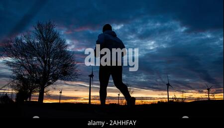 Barsinghausen, Deutschland. 30 Dez, 2019. Ein Mann wird das Tippen bei Sonnenaufgang auf einem Pfad in die Region Hannover. Credit: Julian Stratenschulte/dpa/Alamy leben Nachrichten Stockfoto