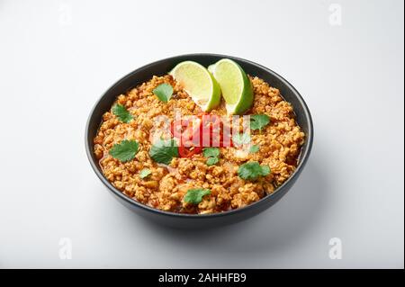 Huhn keema in schwarz Schüssel auf weißem Hintergrund. Kheema ist die indische und pakistanische Küche Teller curry mit Hackfleisch und Gewürzen. Stockfoto