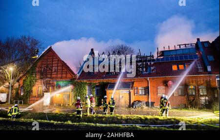 Barsinghausen, Deutschland. 30 Dez, 2019. Feuerwehrmänner ein großes Feuer löschen im Seminarhaus Ökostation Deister-Vorland in Großgoltern in der Region Hannover. Ein Feuer war im ehemaligen Bauernhaus am Morgen, das schnell auf den gesamten Dachstuhl ausgebreitet. Credit: Julian Stratenschulte/dpa/Alamy leben Nachrichten Stockfoto