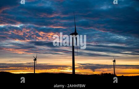 Barsinghausen, Deutschland. 30 Dez, 2019. Die aufgehende Sonne färbt den Himmel hinter Windkraftanlagen in der Region Hannover. Credit: Julian Stratenschulte/dpa/Alamy leben Nachrichten Stockfoto