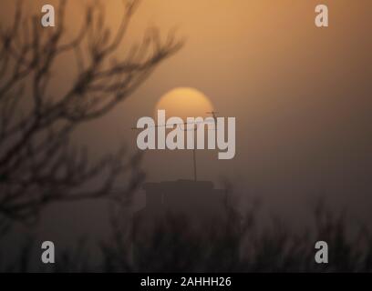 Wimbledon, London, UK. Zum 30. Dezember 2019. Misty dawn Breaks mit eine trübe Sonne über Suburban Dächer in South West London. Credit: Malcolm Park/Alamy Leben Nachrichten. Stockfoto