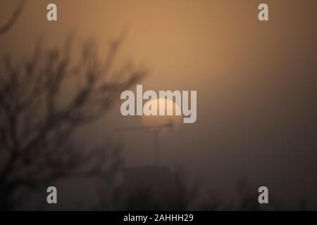 Wimbledon, London, UK. Zum 30. Dezember 2019. Misty dawn Breaks mit eine trübe Sonne über Suburban Dächer in South West London. Credit: Malcolm Park/Alamy Leben Nachrichten. Stockfoto