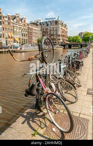 Alte Fahrräder geparkt auf eine Gracht in der Innenstadt von Amsterdam, Niederlande. Stockfoto