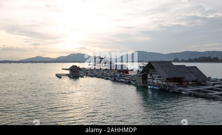 Thai fish Farm in der Mitte auf dem Meer weit entfernt von der Küste, weiche Golden Sunset über Berg im Hintergrund Stockfoto