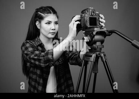 Junge schöne asiatische hipster Frau gegen grauer Hintergrund Stockfoto