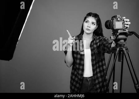 Junge schöne asiatische hipster Frau gegen grauer Hintergrund Stockfoto