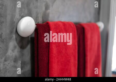 Zwei rote Handtücher im Badezimmer auf einem Trockner. Counter Bad modern. Luxuriöses und elegantes Design Badezimmer mit einem konkreten Mauern. Stockfoto