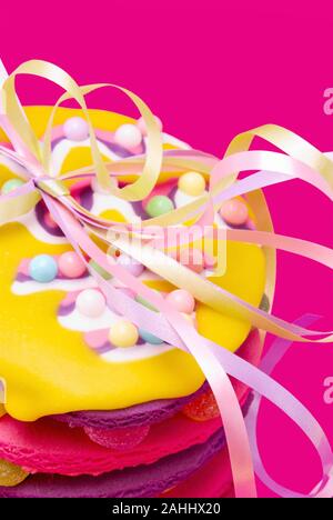 Stapel von bunten Sugar Cookies mit Süßigkeiten besprüht und pastellfarbenen Bänder in einer Schleife gebunden. Der Hintergrund ist strukturierte rosa Material. Stockfoto