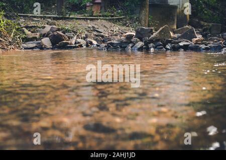 Wehr mit Stein in der Nähe des Flusses mit Reflexion in den Vordergrund gestellt Stockfoto