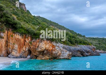 Felsigen Wald Ufer des Meeres bei bewölktem Himmel. Villa am Hang. Gibt es einen natürlichen Steinbogen am Strand Stockfoto