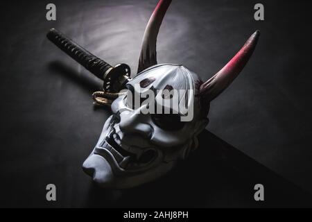 Japanische oni Maske oder riesige Maske, verwendet in Handarbeit aus original zu dekorieren, damit es dunkel und Kunst betrachten, auf Katana Schwert Stockfoto