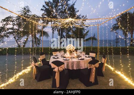 Dinner Table Setup für Hochzeit im Freien bei Nacht mit Blick auf den Strand, mit Lotus Blumen im indischen Stil dekorieren Stockfoto