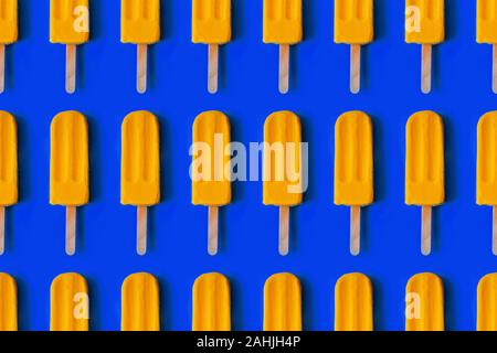 Muster aus hellen gelben mango Eis am trendigen blauen Hintergrund. Sommer Minimalismus Hintergrund. Stockfoto