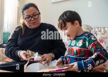 Eine Mutter und jungen Sohn aufgeregt ein Weihnachtsgeschenk gemeinsam öffnen Stockfoto