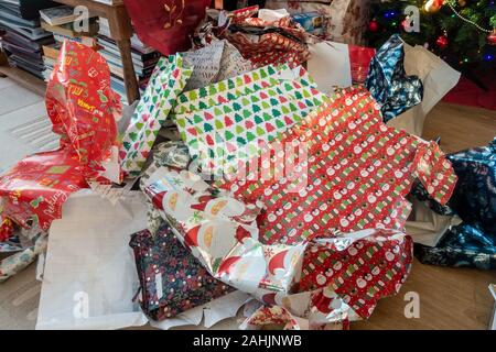 Stapel von weggeworfenen Weihnachten Geschenkpapier links auf dem Boden nach präsentiert geöffnet worden sind. Stockfoto