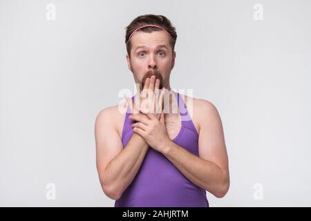 Junger Mann mit Sport violett Sweatshirt schockiert über den Mund mit Händen für Fehler Stockfoto