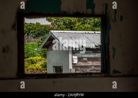 Ansicht des Hauses durch einen alten kaputten Fensterrahmen innen gesehen verlassene Gebäude, Hualien, Taiwan Stockfoto