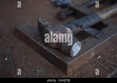 Alte Hammer mit Holzgriff mit Isolierband auf dem Desktop des Master gewickelt. Stockfoto
