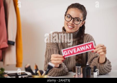 Porträt des zeitgenössischen junge Frau mit Werbegeschenk Wort und in die Kamera lächeln, während Dreharbeiten video für Beauty und Lifestyle channel, kopieren Raum Stockfoto