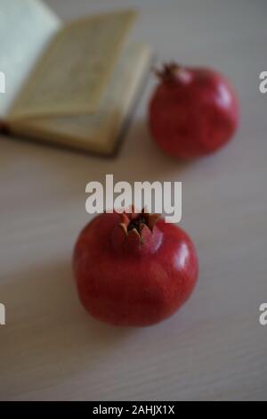 Zwei ganze reifer Granatapfel und eine offene Rezeptbuch auf einem Holztisch. Stockfoto