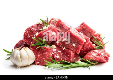 Geschnittenes rohes Rindfleisch mit Rosmarin Kräuter und Knoblauch isoliert auf weißem Stockfoto