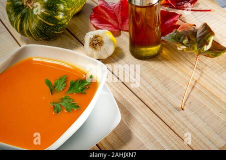 Igh Betrachtungswinkel von Kürbis Ssoup in Schüssel mit herbstlaub am Tisch serviert. Stockfoto