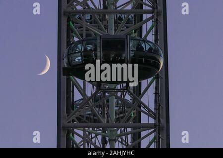 Westminster, London, 30. Dezember 2019. Der Mond hinter dem London Eye Kabinen sichtbar. Ein wunderschön sonnigen Wintertag in London schließt mit einem sanften Pastelltönen Sonnenuntergang in Westminster. Credit: Imageplotter/Alamy leben Nachrichten Stockfoto