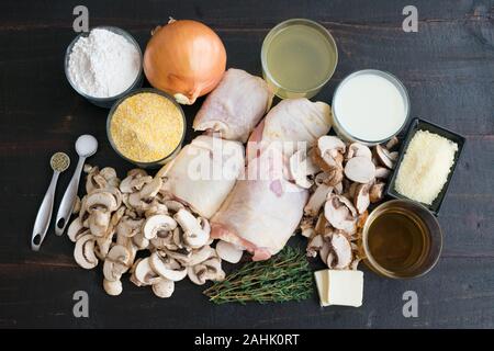 Geschmorte Hühnerkeule mit Pilzen und cremiger Polenta Zutaten: Rohe Hühnerkeule, in Scheiben geschnittenen Champignons, gelb Maismehl, und andere Bestandteile Stockfoto