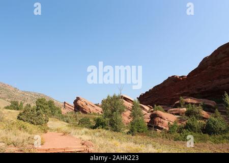 Eine rote Schmutz weg vorbei an wildflower Wiesen und rote Felsformationen ragt aus dem Boden auf der Trading Post Trail im Red Rock State Park, C Stockfoto