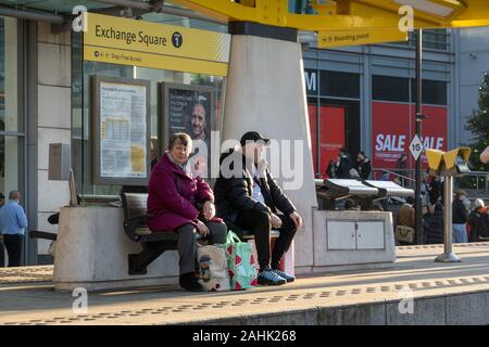 Paar an Exchange Square Straßenbahnhaltestelle, Manchester City Center warten Stockfoto