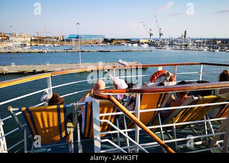 Passagiere einer Fähre auf Liegestühlen entspannen und in Urlaub fahren. Stockfoto