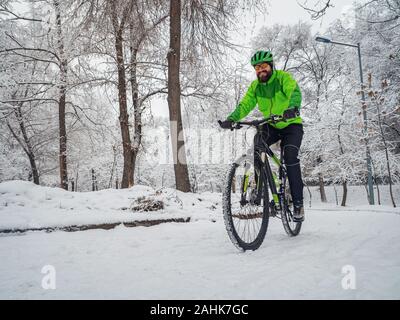 Der Mensch, er reitet ein Fahrrad in einem Winter Park. Aktiv Winter Aktivitäten Stockfoto