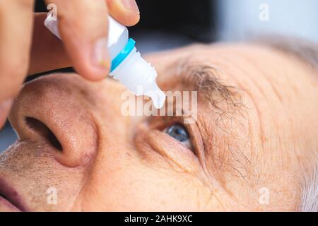 Ältere Person setzt Auge Tropfen in die Augen. Ältere Menschen, Augentropfen Stockfoto