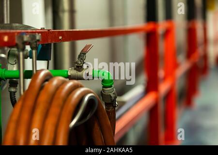 Grün metallic Rohr mit Wasser in der Industrie bei Ventil und orange Rohr selektiven Fokus Nahaufnahme, moderne Sudhaus Brauerei Bier factory Innenansicht Stockfoto